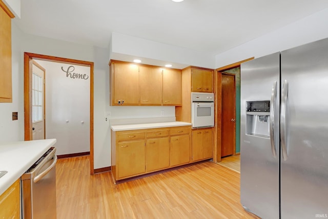 kitchen with stainless steel appliances, light countertops, light wood-style flooring, and baseboards