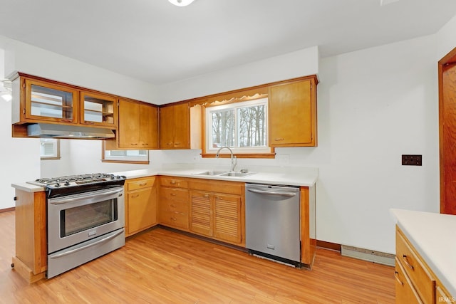 kitchen with stainless steel appliances, brown cabinetry, light countertops, and a sink