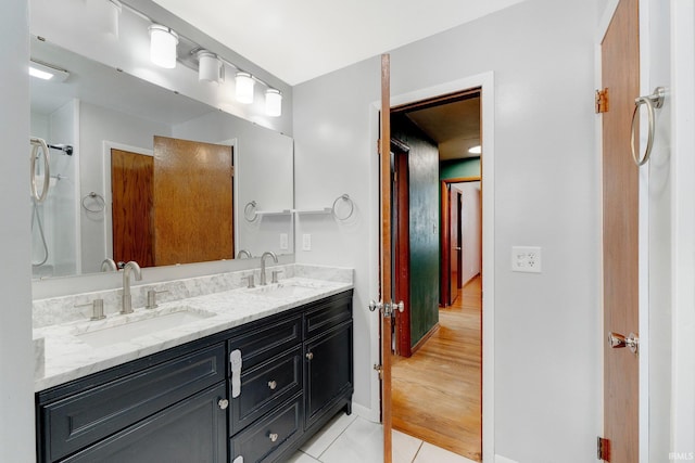 full bathroom with double vanity, baseboards, a sink, and tile patterned floors