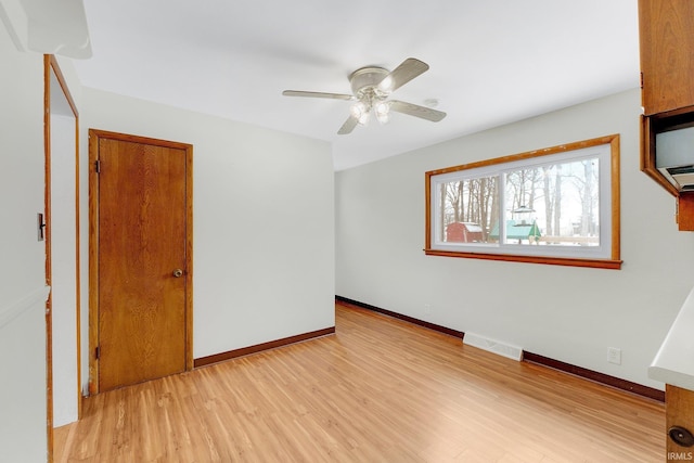 unfurnished room featuring a ceiling fan, light wood-style flooring, visible vents, and baseboards