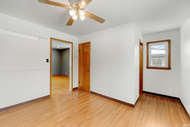 spare room with light wood-type flooring, ceiling fan, and baseboards