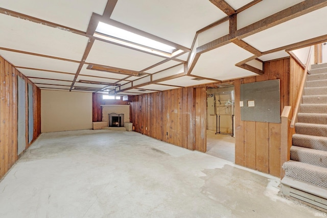 below grade area featuring stairway, wood walls, a fireplace, and electric panel