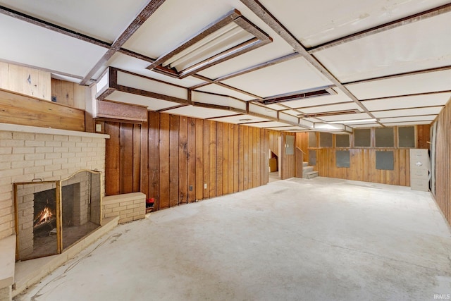 interior space featuring stairs, wood walls, a brick fireplace, and unfinished concrete floors