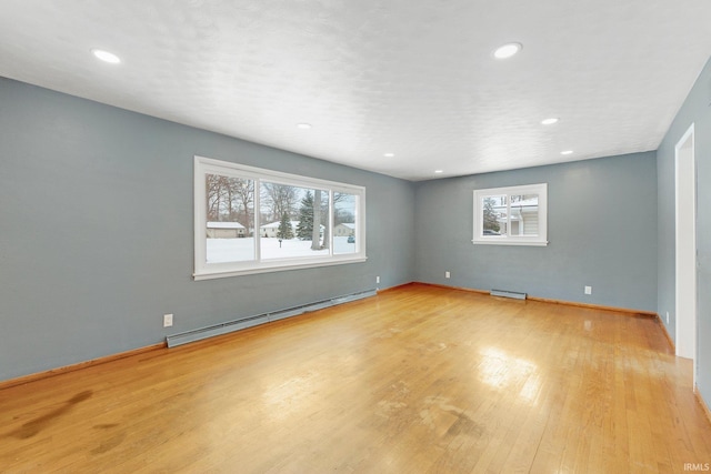 unfurnished room with light wood finished floors, baseboard heating, recessed lighting, and baseboards