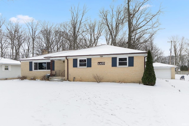 view of front of home featuring an outbuilding, brick siding, a detached garage, and a chimney