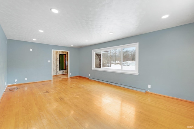 empty room with light wood-style floors, baseboards, baseboard heating, and recessed lighting