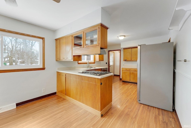 kitchen with a peninsula, visible vents, light countertops, appliances with stainless steel finishes, and glass insert cabinets