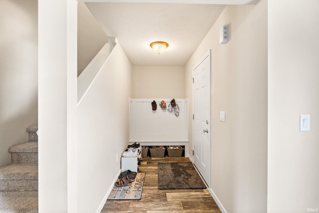 doorway featuring stairs, baseboards, and wood finished floors