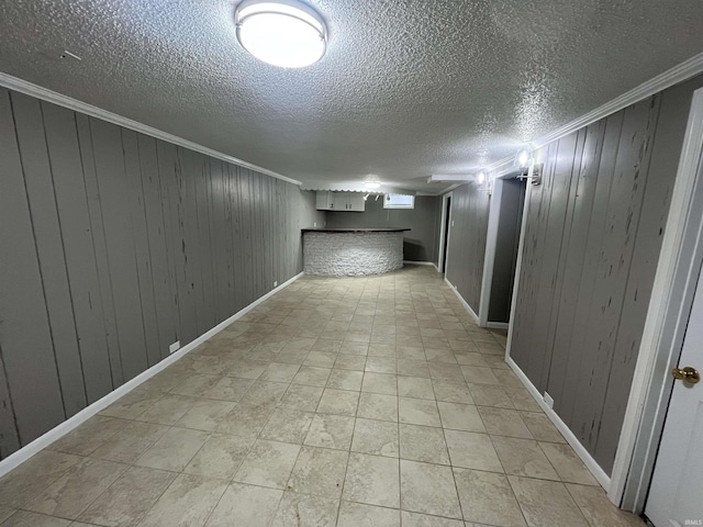 finished basement featuring baseboards, ornamental molding, and a textured ceiling