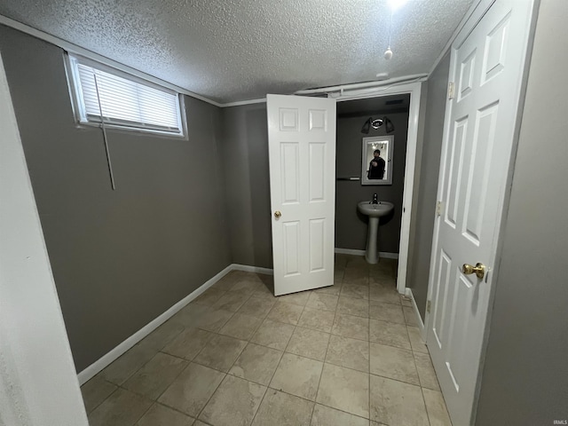 interior space with a textured ceiling, light tile patterned flooring, and baseboards