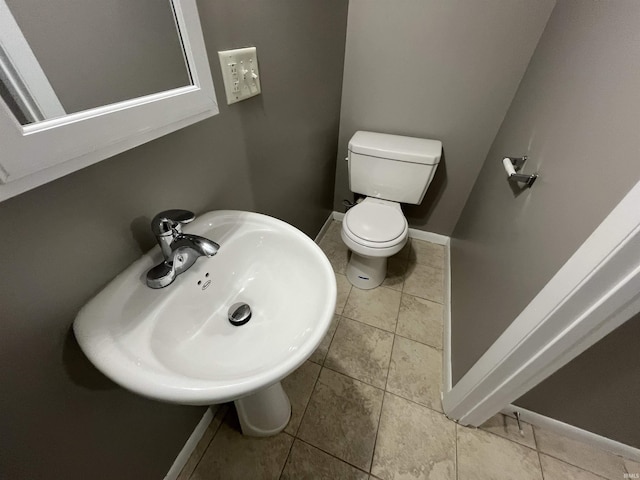 bathroom with toilet, baseboards, a sink, and tile patterned floors