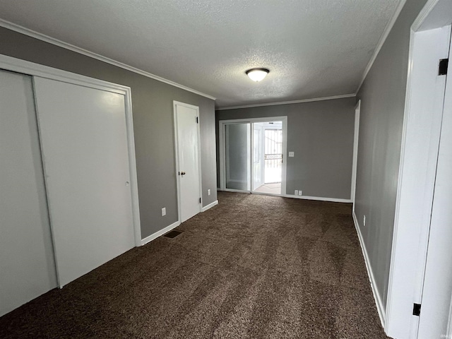 unfurnished bedroom with baseboards, visible vents, ornamental molding, dark colored carpet, and a textured ceiling