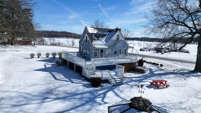 snow covered property featuring a deck, stairway, and a chimney