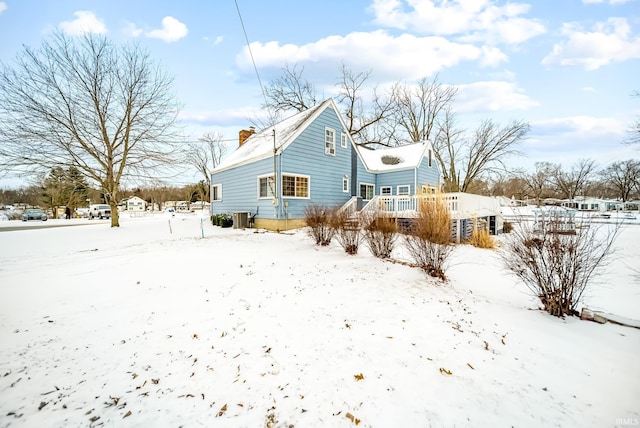 snow covered house with cooling unit and a chimney