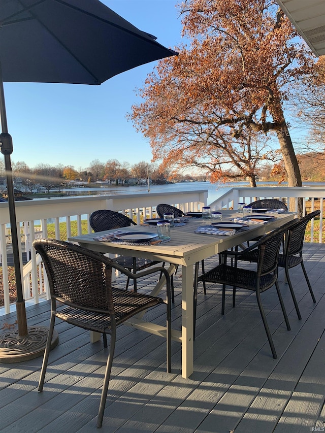 wooden deck with a water view and outdoor dining area