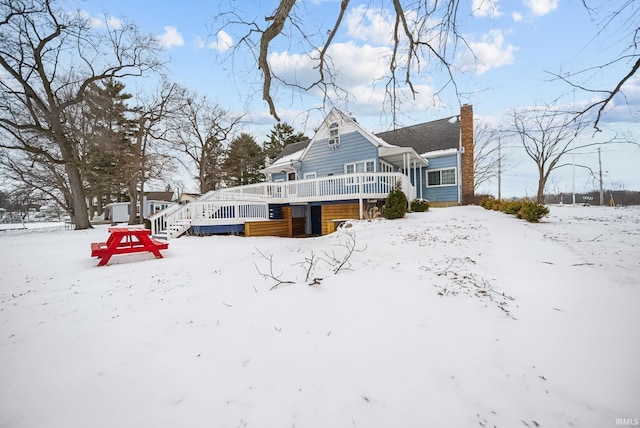 snow covered rear of property featuring a chimney and a deck