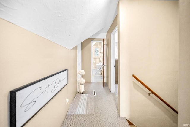 corridor with lofted ceiling and an upstairs landing