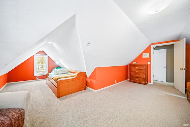 bedroom with lofted ceiling, light colored carpet, and baseboards