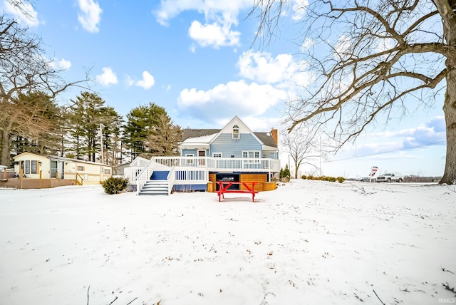 snow covered house featuring stairway, a chimney, and a deck