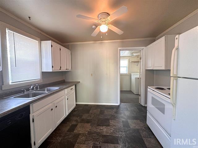 kitchen featuring dark countertops, washer / clothes dryer, white cabinets, a sink, and white appliances