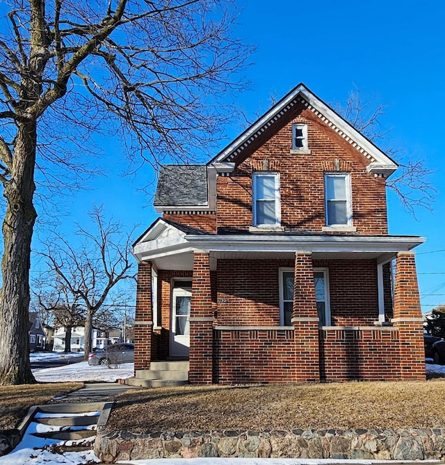 traditional-style house featuring covered porch and brick siding