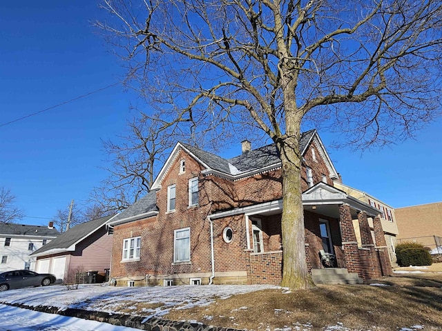 view of front of property with a garage, driveway, brick siding, and a chimney