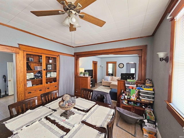 dining room featuring ornamental molding, light tile patterned floors, baseboards, and a ceiling fan