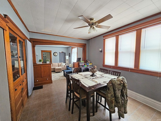 dining area featuring a ceiling fan, crown molding, and baseboards