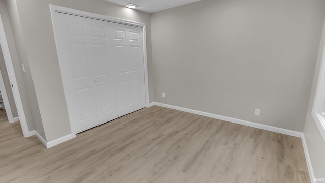 unfurnished bedroom with light wood-type flooring, baseboards, and a closet