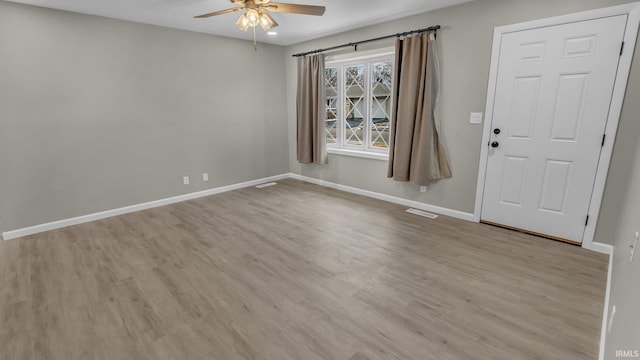 spare room with ceiling fan, visible vents, light wood-style flooring, and baseboards