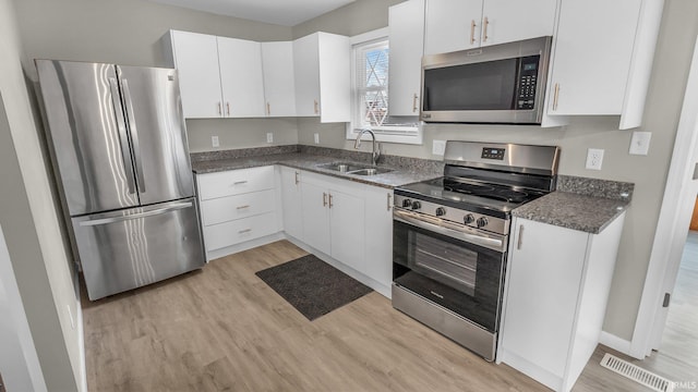 kitchen featuring stainless steel appliances, a sink, and white cabinetry