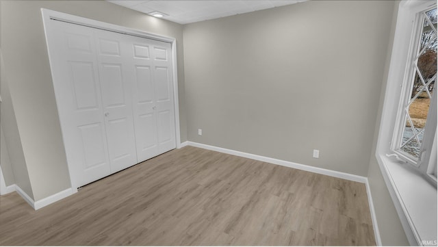 unfurnished bedroom with light wood finished floors, baseboards, and a closet