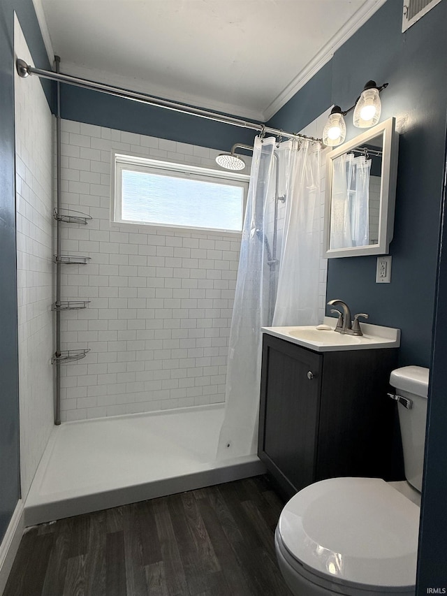 full bathroom featuring a stall shower, toilet, wood finished floors, crown molding, and vanity