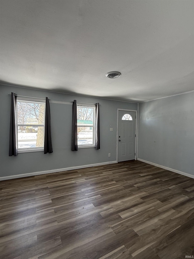 foyer featuring dark wood-type flooring, visible vents, and baseboards