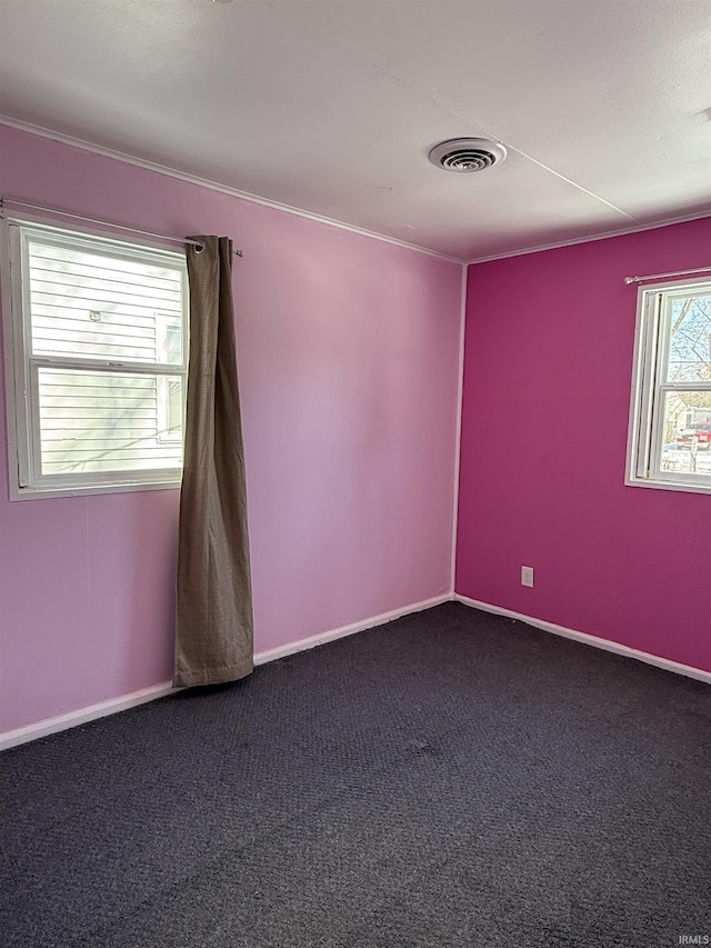 spare room featuring baseboards, visible vents, and dark carpet