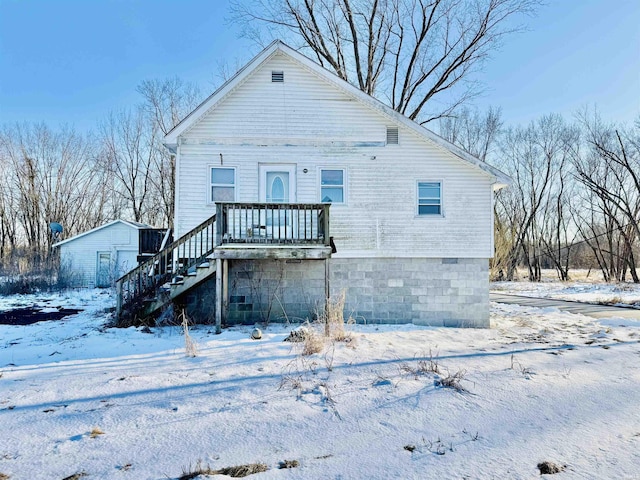 snow covered rear of property with an outbuilding, a storage shed, and stairs