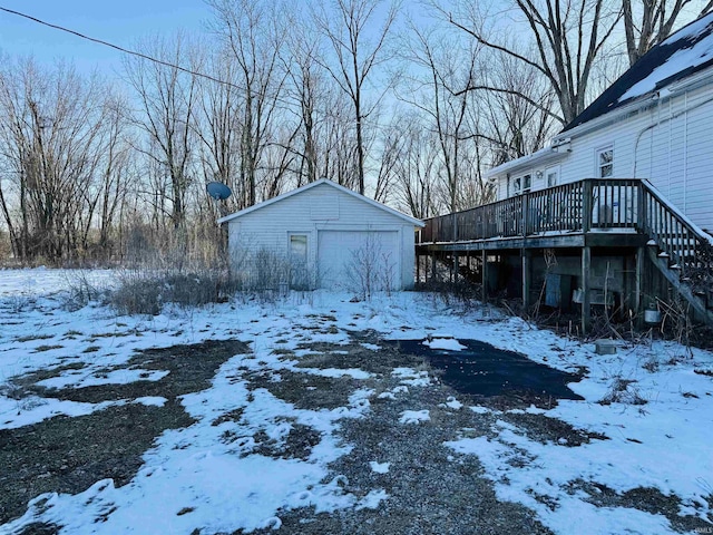 yard layered in snow featuring an outdoor structure, a detached garage, and a wooden deck