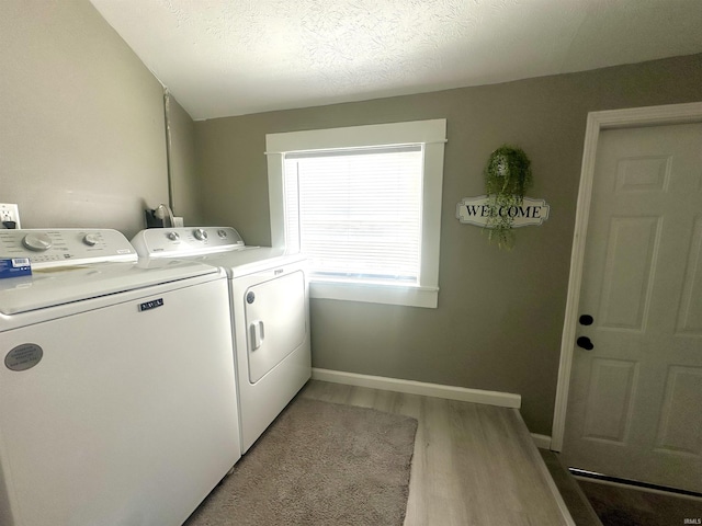 clothes washing area with laundry area, baseboards, wood finished floors, a textured ceiling, and washer and dryer