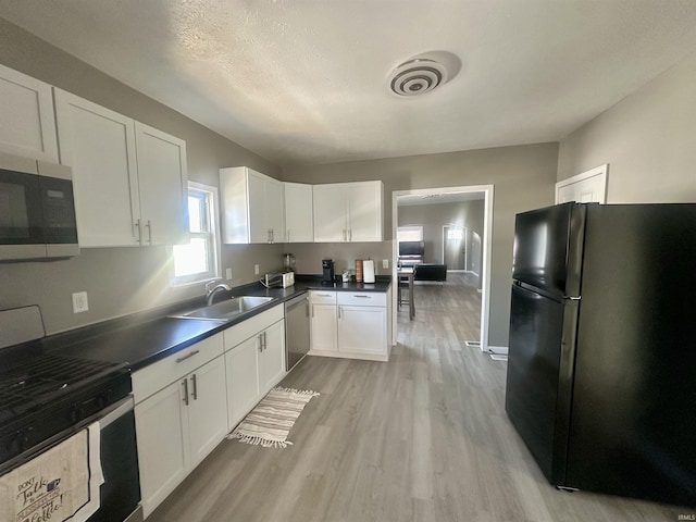 kitchen with stainless steel appliances, a sink, visible vents, white cabinetry, and dark countertops