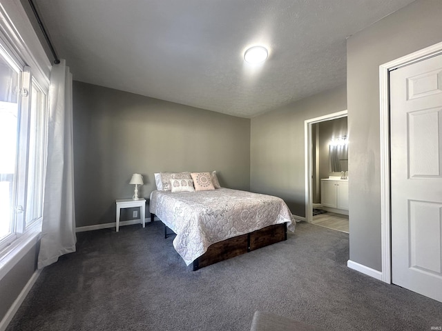 bedroom with ensuite bath, multiple windows, baseboards, and dark colored carpet