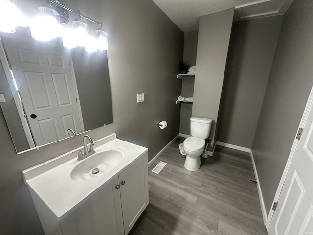 bathroom with toilet, baseboards, wood finished floors, and vanity