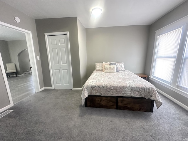 carpeted bedroom featuring arched walkways, visible vents, and baseboards