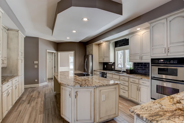 kitchen featuring light stone counters, a center island, stainless steel appliances, and a sink