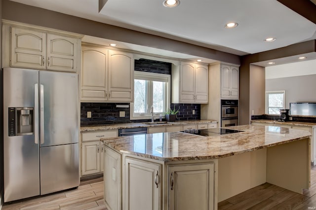 kitchen featuring black appliances, a kitchen island, and light stone counters