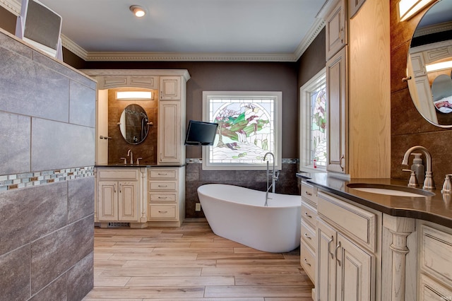 bathroom featuring a freestanding tub, two vanities, a sink, and tile walls