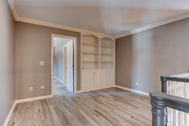 interior space with ornamental molding, light wood-style flooring, and baseboards