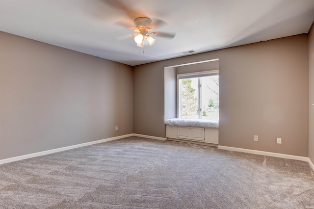 carpeted empty room with a ceiling fan, visible vents, and baseboards