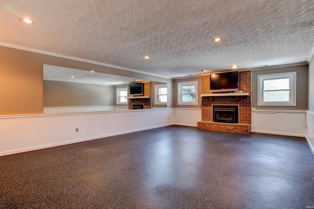 unfurnished living room with wainscoting, ornamental molding, a textured ceiling, a fireplace, and recessed lighting