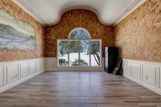 unfurnished room featuring a wainscoted wall, lofted ceiling, and light wood-style floors