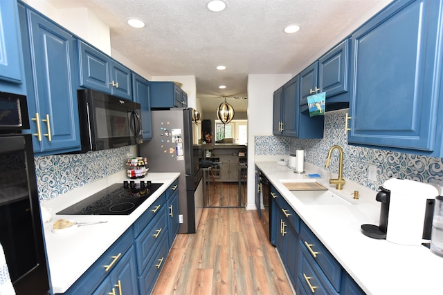 kitchen with light countertops, a sink, blue cabinetry, and black appliances